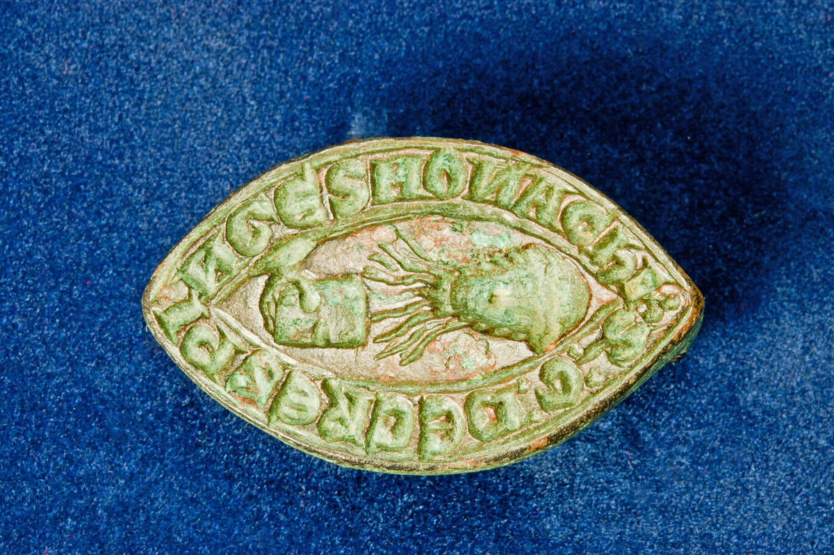 Matrix detail on medieval lead wax seal engraved with central head and inscription