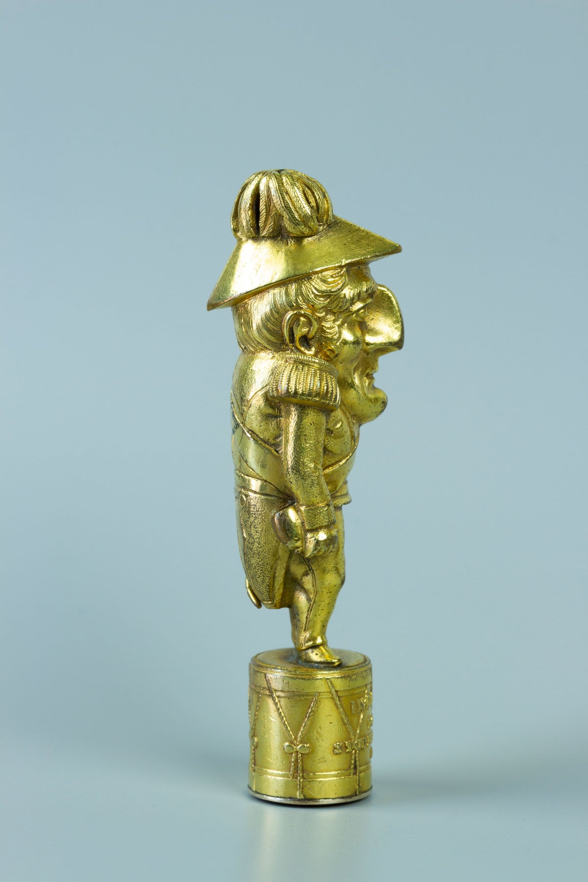 Side profile of wax seal caricature of Wellington standing on a drum
