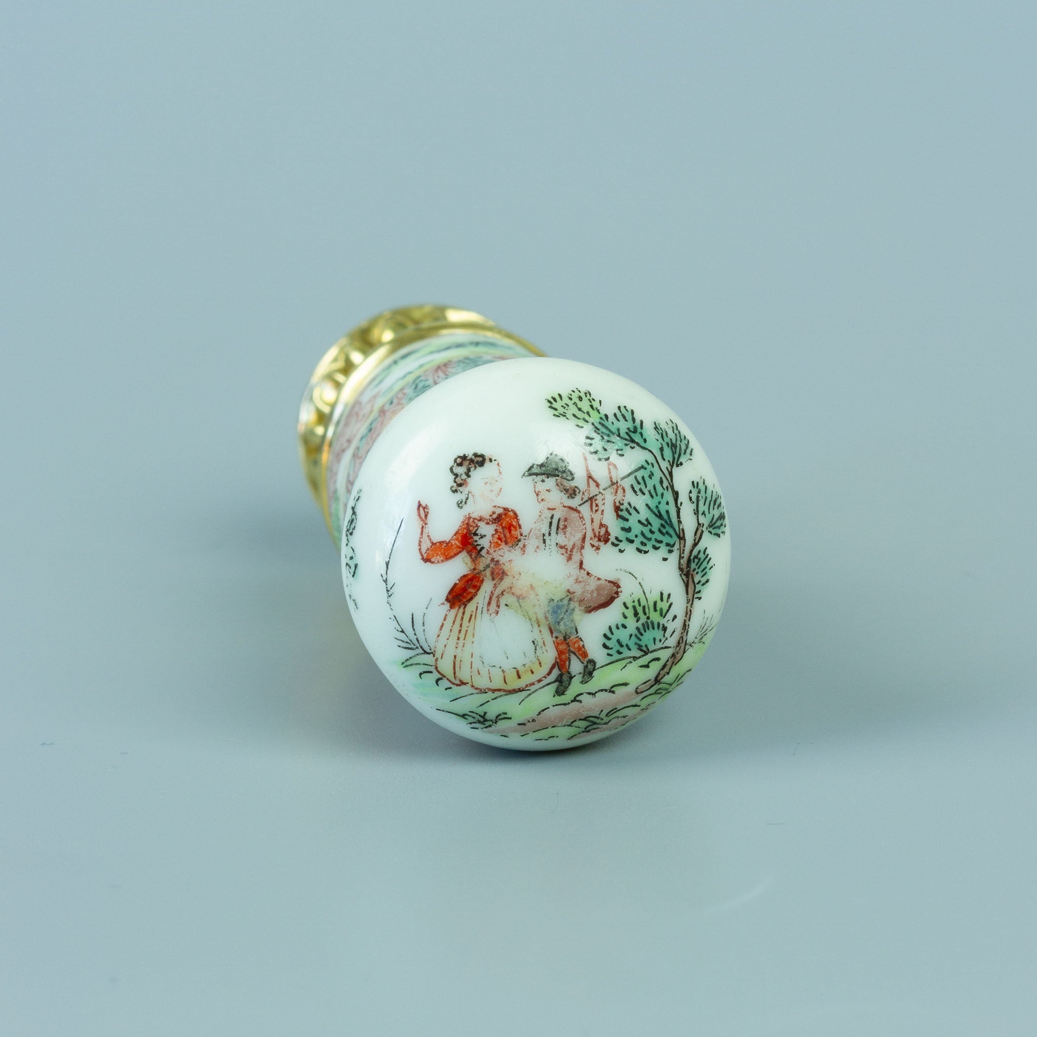 Top of white porcelain seal handle with painting of man and woman in pastoral scene